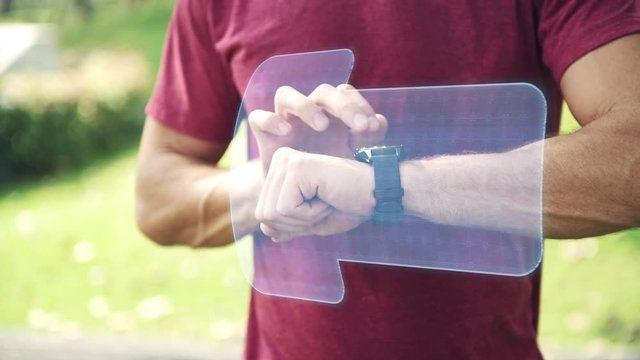 Man using high tech smart watch in park. Young white man accessing his smart watch with holographic display special effects overlay panel for other use. Future technology concept. - Powered by Adobe