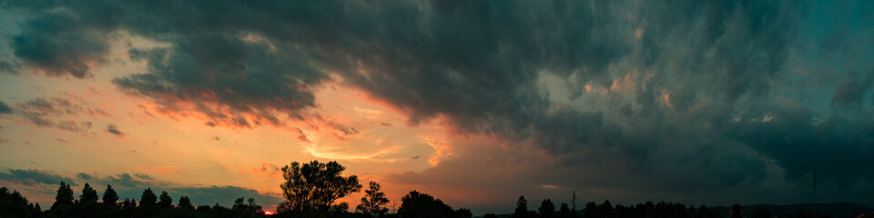 Fototapeta na wymiar Dark sky panorama with orange sunset clouds