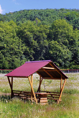 Wooden gazebo with a red roof under a bright scorching summer sun