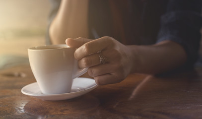 The hand of a woman holding a cup of coffee.