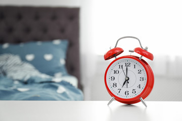 Analog alarm clock on table in bedroom. Time of day © New Africa
