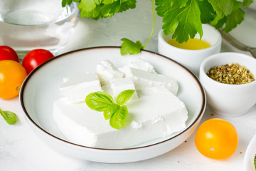 Fresh Greek feta cheese in a bowl whole and slices for salad with vegetables
