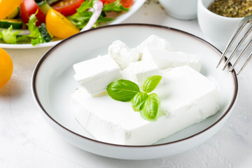 Fresh Greek feta cheese in a bowl whole and slices for salad with vegetables