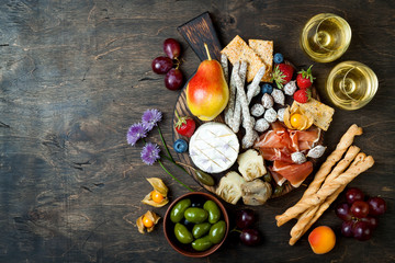 Appetizers table with italian antipasti snacks and wine in glasses. Cheese and charcuterie variety...