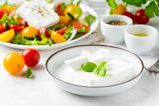 Fresh Greek feta cheese in a bowl whole and slices for salad with vegetables