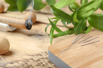Wooden board with needles for acupuncture on table, closeup - obrazy, fototapety, plakaty