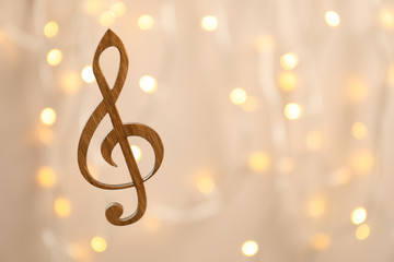 Wooden treble clef against blurred lights. Christmas music concept