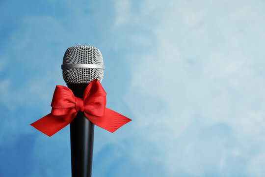 Microphone with bow on color background. Christmas music concept