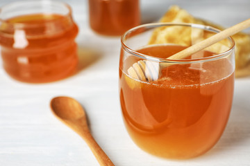Glass jar with sweet honey and dipper on table, closeup