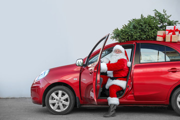 Fototapeta premium Authentic Santa Claus in car with gift boxes and Christmas tree, view from outside