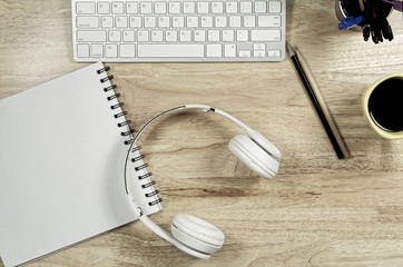 White headphones stack on white book paper on the wooden table
