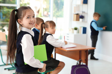 Little girl in classroom. Stylish school uniform