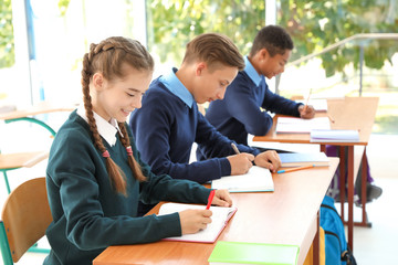 Teenage students in classroom. Stylish school uniform