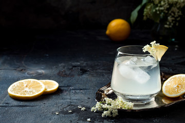 A glass of homemade elderflower gin sour or lemonade garnished with freshly picked elderflowers. - obrazy, fototapety, plakaty