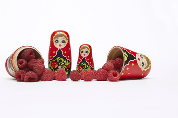 Traditional wooden doll's Matreshka Babushka with raspberries isolated on a white background