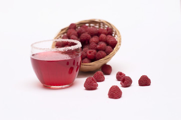 Raspberries in a wicker basket and raspberry juice on a white background