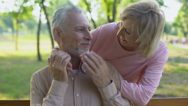 Woman playfully closing husband eyes, meeting outdoors, happiness in old age
