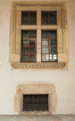 Obraz premium Part of the wall of an ancient castle with windows with bars. The wall of an ancient castle with windows as a texture for graphic design.