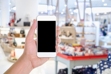 A man hand holding smart phone device wih blank copy space screen  in a department store or shopping mall