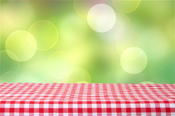 Empty table with red checkered tablecloth and bright green bokeh background. For your food and...