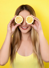 Young smiling woman holding slices of lemon