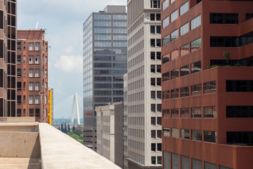 View of city street with high buildings and bridge in the distance