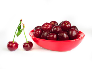 Ripe cherries in a red plate on a white background