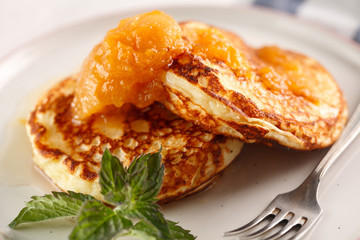 Cottage cheese pancakes, syrniki, curd fritters. Breakfast on white background cheesecake and apricot jam.