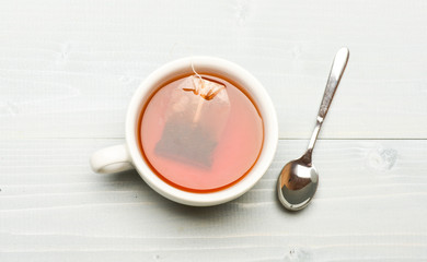 Process of black tea brewing in ceramic mug, top view. Mug filled with hot water and dipped bag of black tea. Tea brew concept. Mug filled with boiling water, teabag and spoon on white background