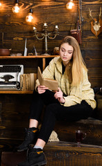 Woman writer in library at home creative occupation reading book. Girl in casual outfit sits with...