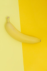 Creative view of a banana on a background of similar colors. Yellow background.