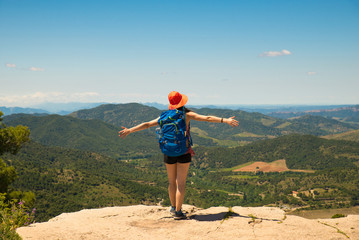 Backpacker adventurer girl admiring the landscape from top of a cliff