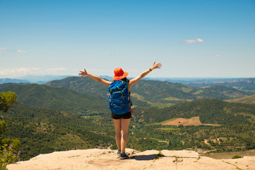 Backpacker adventurer girl admiring the landscape from top of a cliff