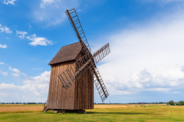 Fototapeta na wymiar Old wooden windmill on field in summer day.