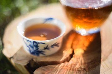 Healthy beverage. Hot black tea in Chinese cups on wood slab in bright morning sun