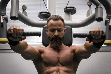 Hombre fuerte con grandes músculos entrenando pecho en el gimnasio. Ponerse en forma.