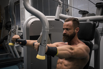 Hombre fuerte con grandes músculos entrenando pecho en el gimnasio. Ponerse en forma.