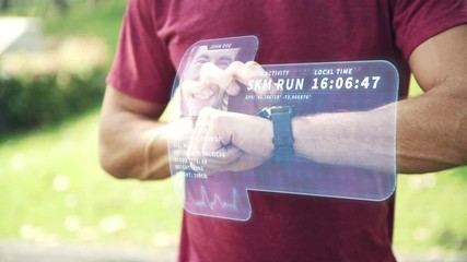 Man using high tech smart watch in park. Young white man accessing his smart watch with holographic display special effects overlay panel for other use. Future technology concept. - Powered by Adobe