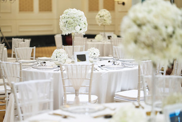 White roses, flower bouquet on the long vase decoration on luxury wedding reception dinner table