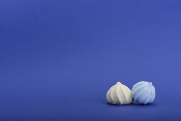 Yellow and blue meringues isolated on blue background with space for text