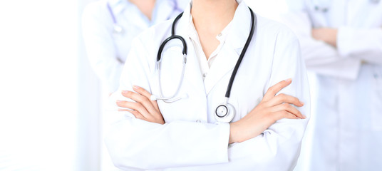 Unknown female doctor with medical staff  at hospital. Teamwork in medicine