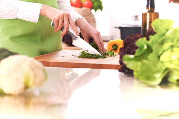 Close Up of human hands cooking vegetable salad in kitchen on the glass table with reflection. Healthy meal, and vegetarian food concept
