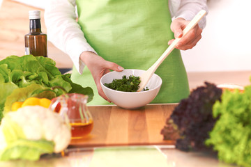 Close Up of human hands cooking vegetable salad in kitchen on the glass table with reflection. Healthy meal, and vegetarian food concept