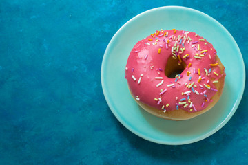 Fototapeta na wymiar Pink Doughnut with Sprinkles on Blue 