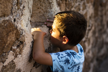 Little boy looking through the wall of a castle