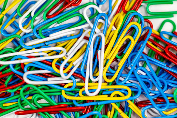Colorful paperclips bunched up on a white surface.