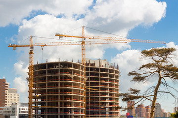 Civil engineering of building construction site with tower block and crane near to trees.