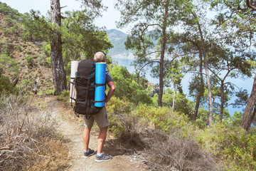 Obraz premium An elderly tourist with a backpack on the hiking trail