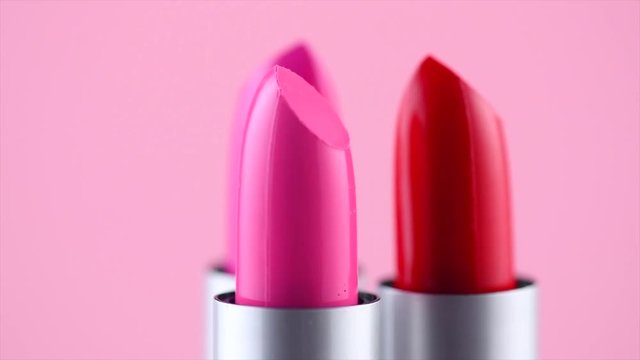 Lipstick tints palette. Fashion colorful lipsticks rotated over pink background. Professional makeup and beauty. 4K UHD video footage. 3840X2160