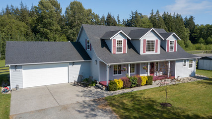 Cute home exterior with red shutters on a summer day.